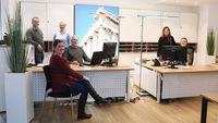 Das Team von Emmaus-Reisen hat sich um die Schreibtische im Büro und Verkaufsraum aufgestellt.