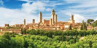 Die vielen Geschlechtertürme von San Gimignano ragen über den Feldern der Olivenbäume in den böauen Himmel.