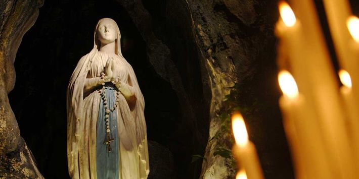 Die Mariengrotte in Lourdes als Andachtsort mit brennenden Kerzen.